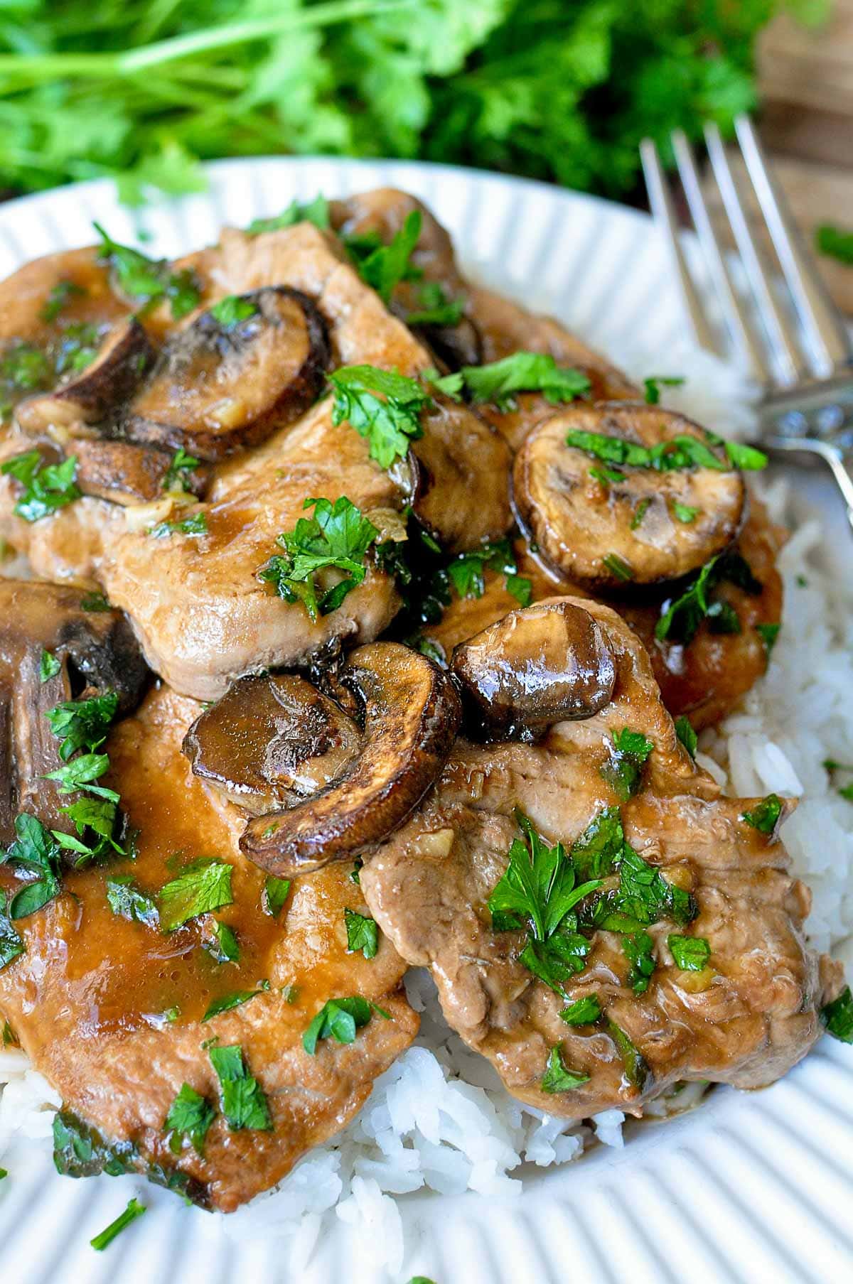 Pork Tenderloin Medallions and mushrooms over rice on plate.