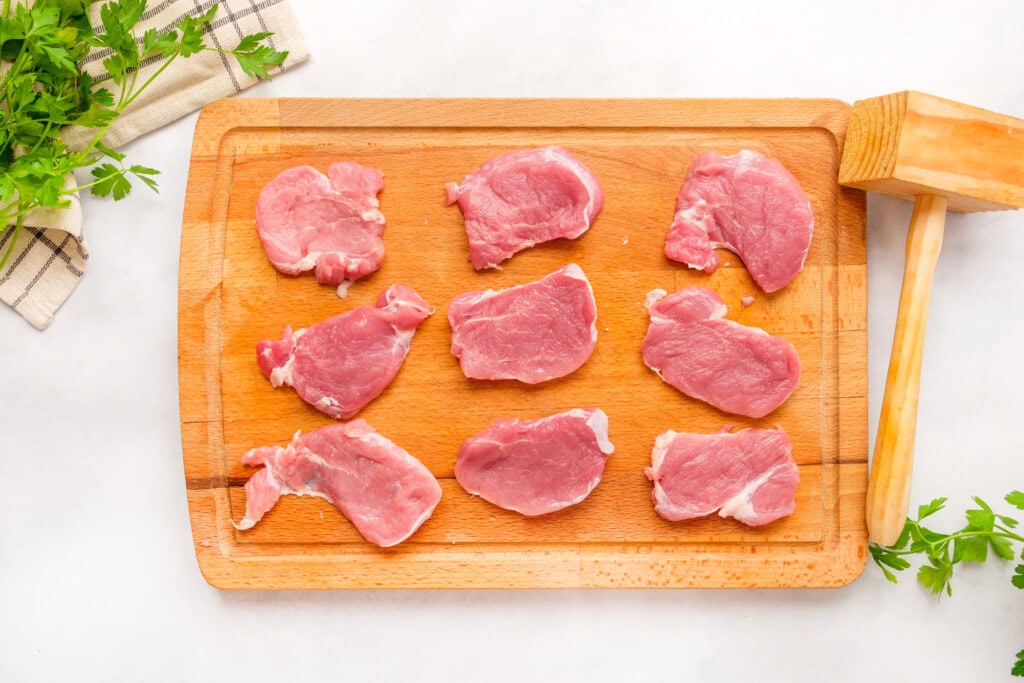 Pounding pork tenderloin medallions with a meat mallet.