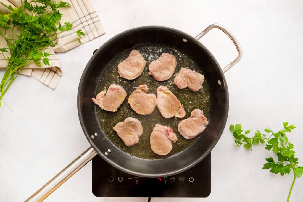 Pork tenderloin medallions cooking on second side.