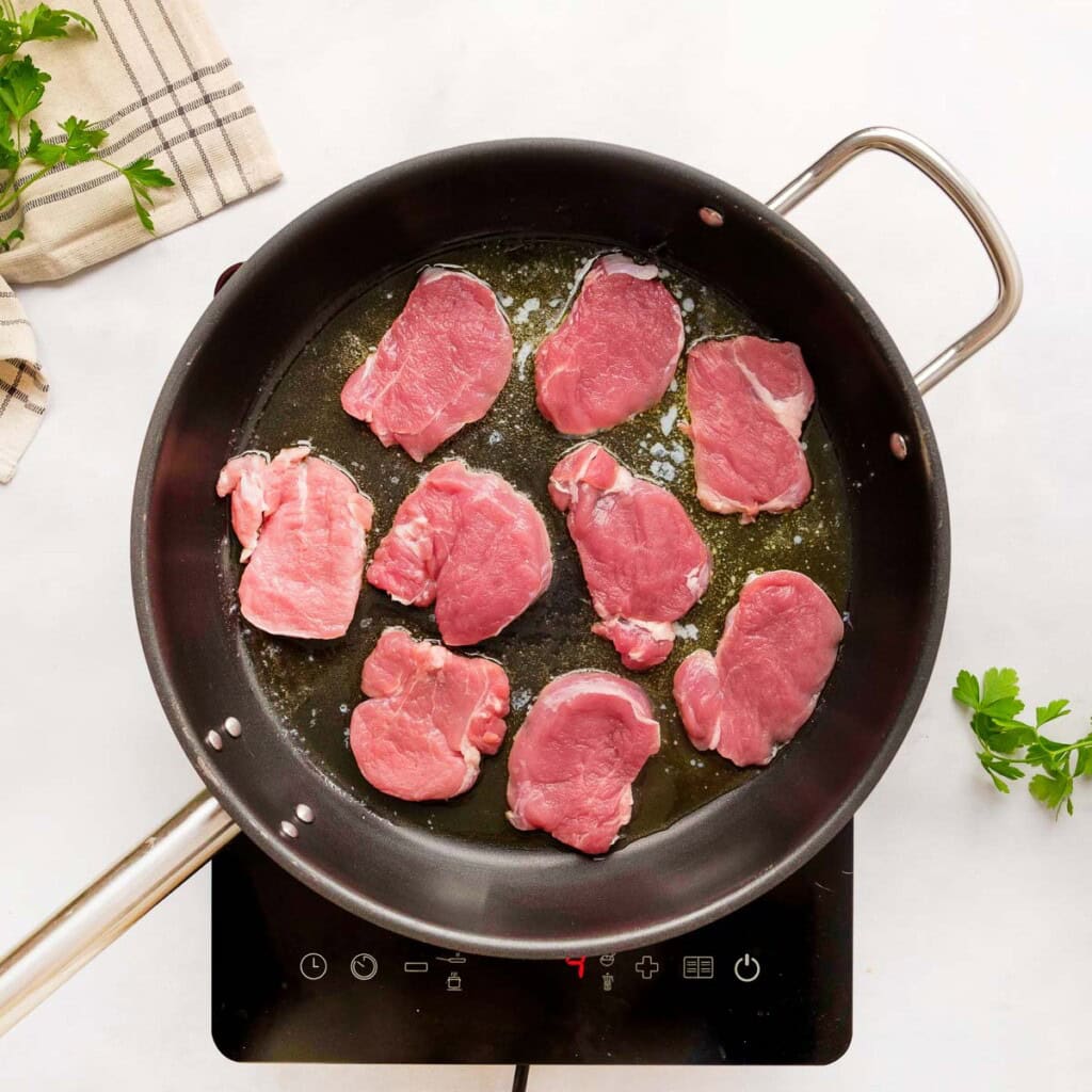 Browning pork tenderloin medallions in skillet.