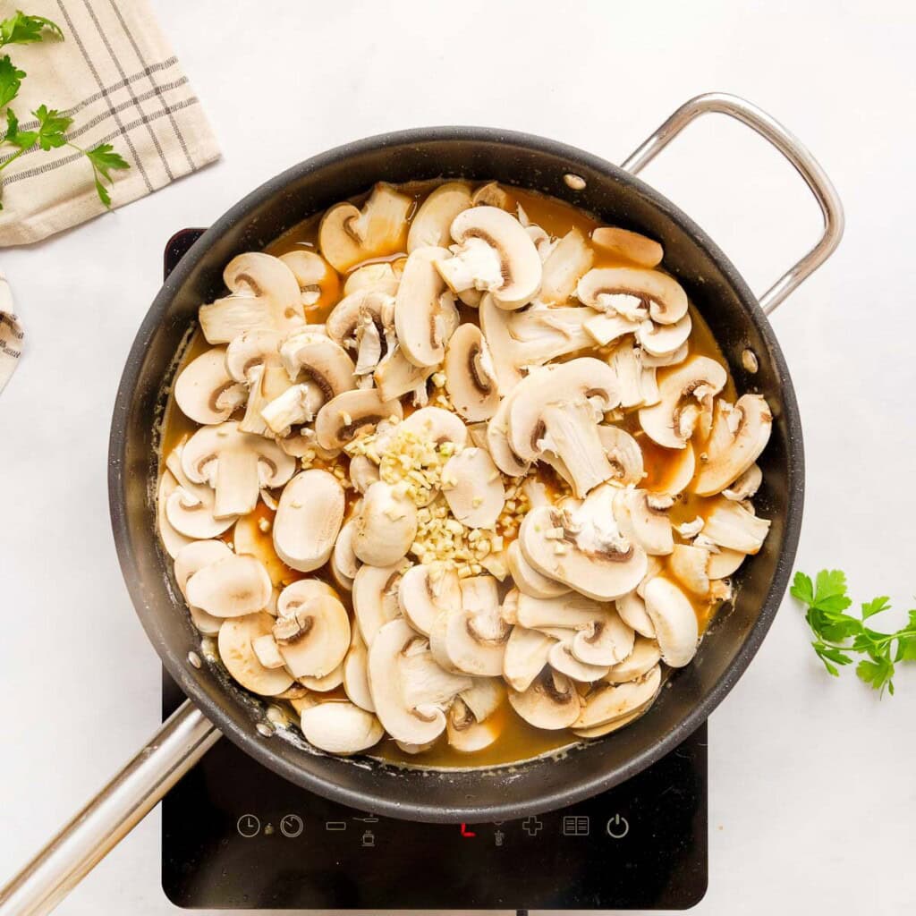 Adding mushrooms and garlic to Pork Tenderloin Medallions recipe.