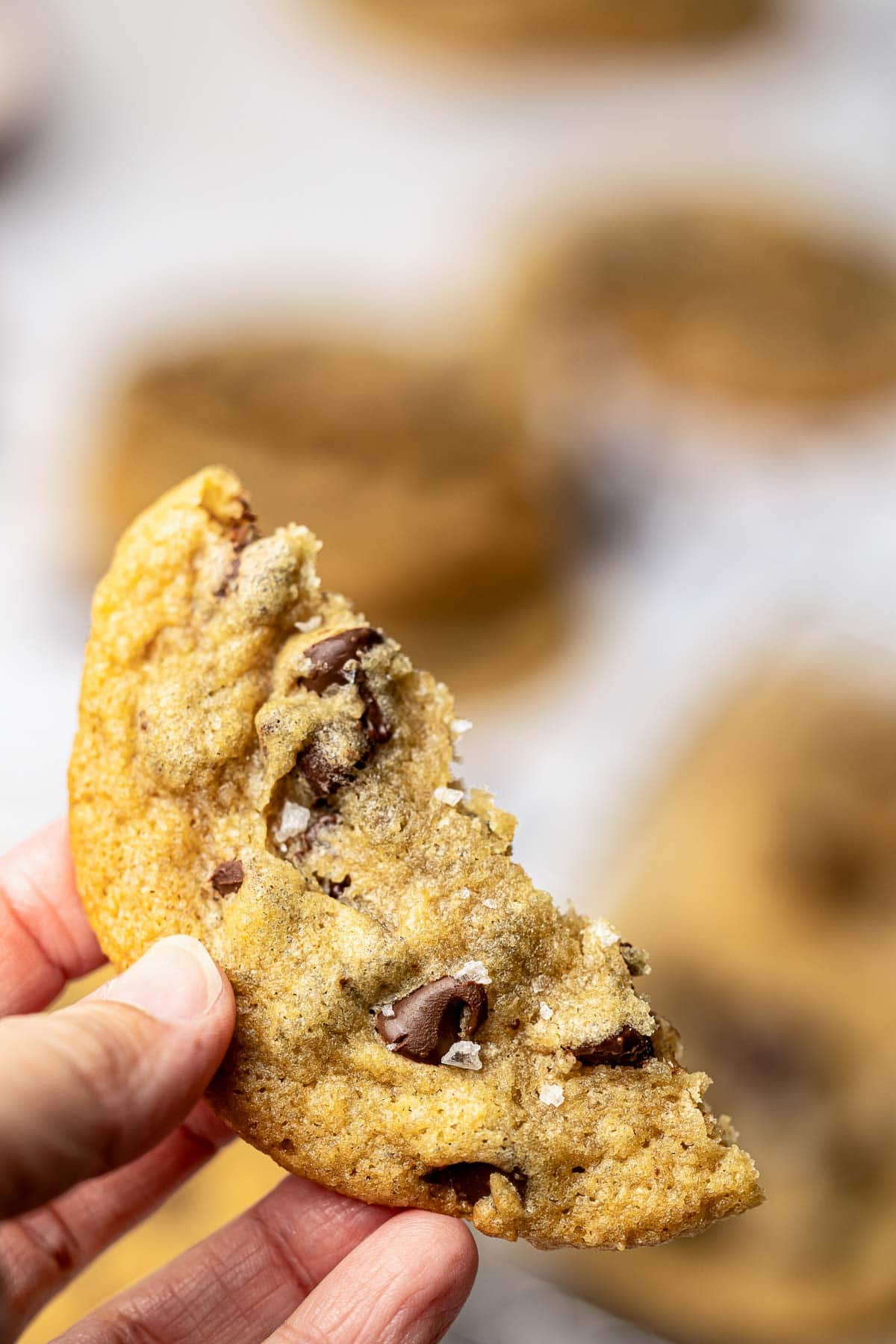 Brown Butter Chocolate Chip Cookies broken in half and held in hand.