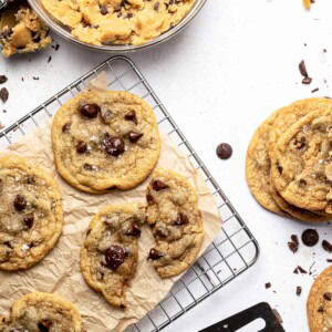 Brown Butter Chocolate Chip Cookies on cooling rack and table with extra cookie dough in bowl.